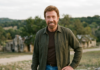 Chuck Norris Dies at 86: Full Story, Career & Truth About Heart Attack Rumors Chuck Norris smiling outdoors in a casual outfit with a scenic background